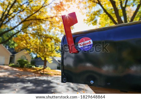 Mailbox with an "I voted today" sticker on it with sun flare behind flag, absentee voting through the mail Royalty-Free Stock Photo #1829648864