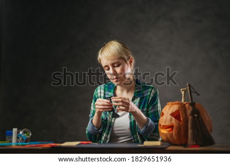 Young mother making DIY Halloween decorations for kids. Preparing at home celebration with handicrafts.
