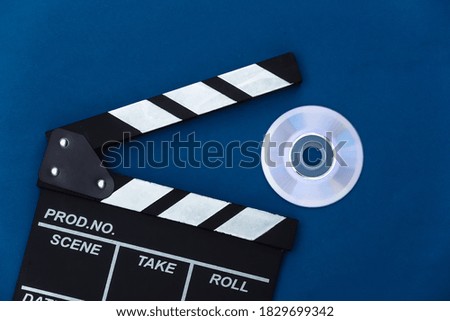 Film clapper board and cd on classic blue background. Cinema industry, entertainment. Top view