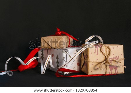 gift boxes Packed in wrapping paper and tied with ribbons for the new year or Christmas lie in a pile on a black background