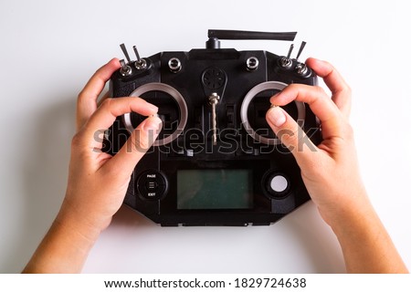 Black remote control panel and hands on controls for drone. Top view on white background. Horizontal orientation. High quality photo
