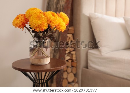 Beautiful autumn flowers on table in cozy bedroom interior. Space for text