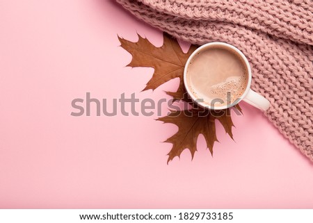 Autumn cozy composition. Dry brown leaves, hot chocolate, pink knitted sweater on pink pastel background. Fall concept copy space