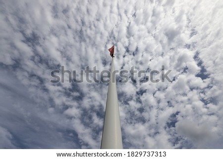 The American flag in top from below against a beautiful background of blue sky and white clouds.
