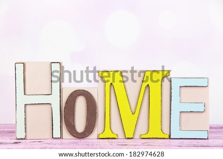 Decorative letters forming word HOME on table on bright background