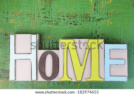 Decorative letters forming word HOME on wooden background