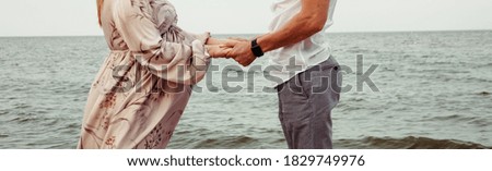 A loving couple holding hands on the background of the sea. Close-up photo, place for an inscription
