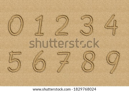 Numbers written in sand on a beach.