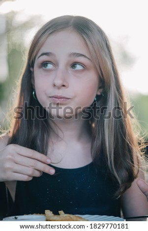 Beautiful laughing little girl sitting at table and eating French fries from your plate. Teenage girl eating French fries. happy little girl eating a french fries.