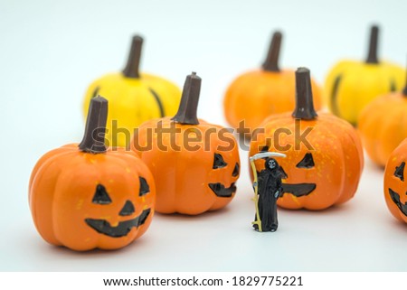 Closeup of Death devil miniature figure standing with halloween  pumpkin face jack on white background.