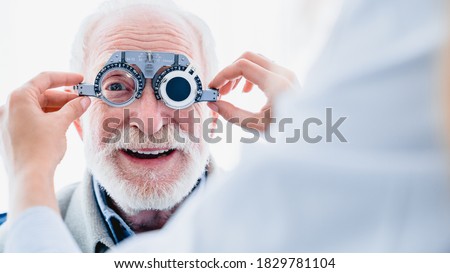 Smiling elderly man checking up vision with special ophthalmic glasses Royalty-Free Stock Photo #1829781104