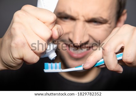 man try hard to squeeze rest out of empty tube of toothpaste  Royalty-Free Stock Photo #1829782352