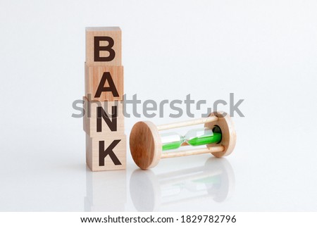 hourglass and wooden blocks with the word Bank. The concept of financial Bank. Investing in a business project. Property insurance.