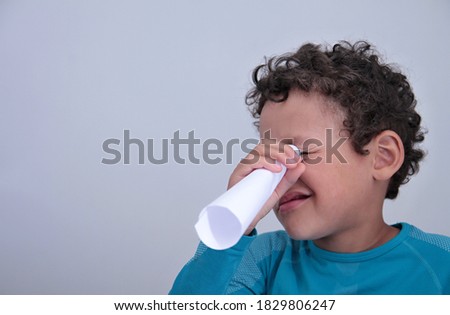 boy looking through white paper on grey background stock photo