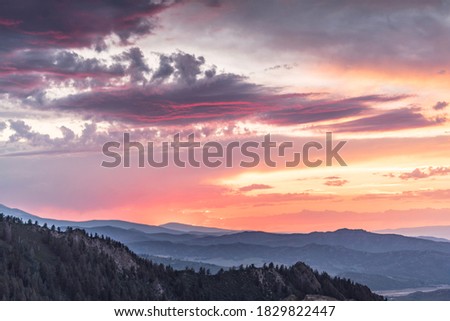 A very warm sunset casts natural light over the mountain forest below. Photo taken at sunset from the top of Aspen mountain in Aspen, Colorado. 