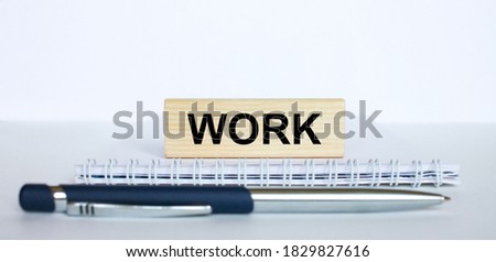 The word Work on a bar of wood, lying on a Notepad with a metal blue pen. Business concept photo