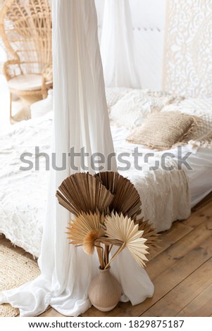 Boho-style bedroom interior. Exic holiday in Bali. A modern bed with palatn and pillows. interior of the room. design. flowers in a vase on the floor