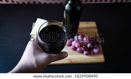 holding glass of red wine