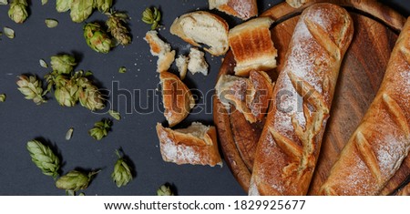Fresh organic homemade bread from hop sourdough on black stone background. Natural french baguette. Rural kitchen or bakery concept.
Top view. Flat lay.