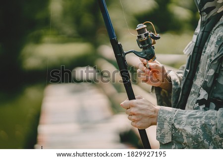 A man fishing on a lake. Guy in a uniform.