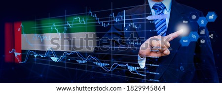Businessman touching data analytics process system with KPI financial charts, dashboard of stock and marketing on virtual interface. With United Arab Emirates flag in background.