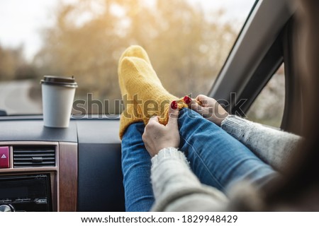 Woman in a car in warm woolen yellow socks on the car dashboard. Cozy autumn weekend trip. The concept of freedom of travel