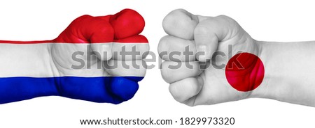 The concept of the struggle of peoples. Two hands are clenched into fists and are located opposite each other. Hands painted in the colors of the flags of the countries. France vs Japan