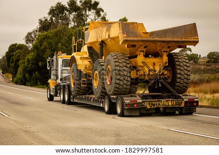 A very large haul dump truck being hauled by an 18 wheel truck down a freeway Royalty-Free Stock Photo #1829997581