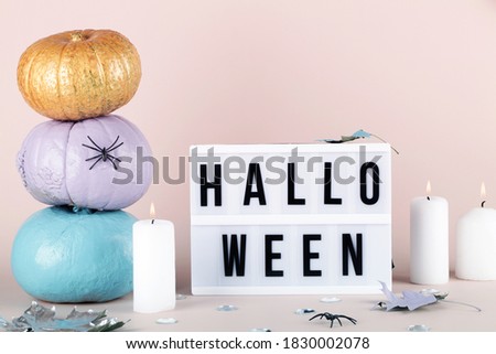  lightbox with halloween text and blue purple and gold pumpkins with candles on pink background. Holiday greeting , invitation concept. 