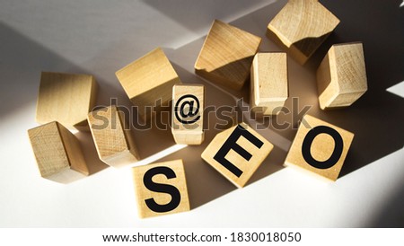 Wooden cubes with letters SEO and sign, on a white table. Many cubes