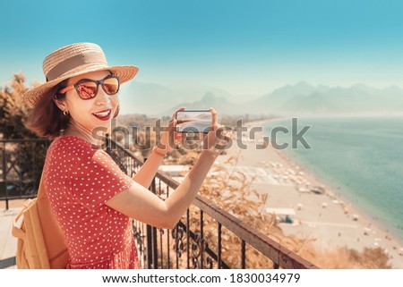 Happy woman travel blogger takes quality photos of the seacoast and Konyaalti beach in Antalya, Turkey