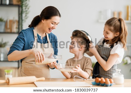 Happy loving family are preparing bakery together. Mother and children daughters girls are cooking cookies and having fun in the kitchen. Homemade food and little helper. 