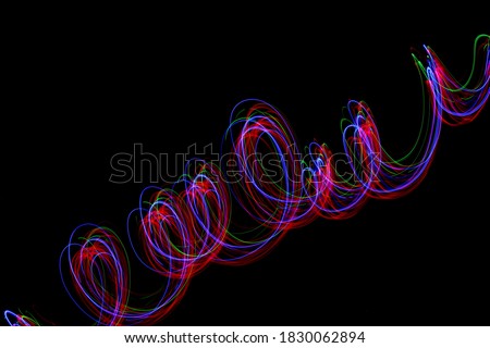 Long exposure photograph of neon colour in an abstract swirl, parallel lines pattern against a black background. Light painting photography.