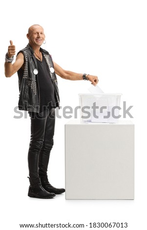 Full length portrait of a punk putting a vote in an election box and showing thumbs up isolated on white background