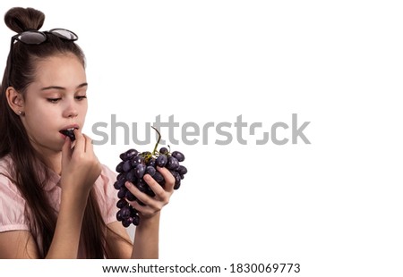 A teenage girl holds grapes in her hand, fresh, sweet and wants to eat them. Isolated.