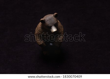 Toy brown bear on a dark background. Plastic toy