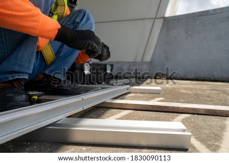 worker wear all safety suit insatlling metal frame on rooftop stock photo