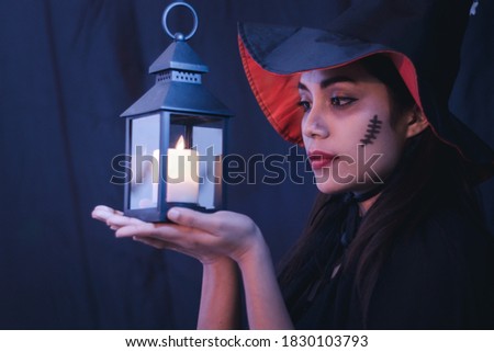 Halloween witch woman portrait holding candle lamp, fashion young woman going to party with spooky costume, makeup scary faces, having fun at Halloween party by celebration