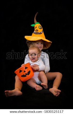 Baby And Boy Who Are Brothers With Pumpkin Hat And Pumpkin At Halloween Party. Trick Or Treating.