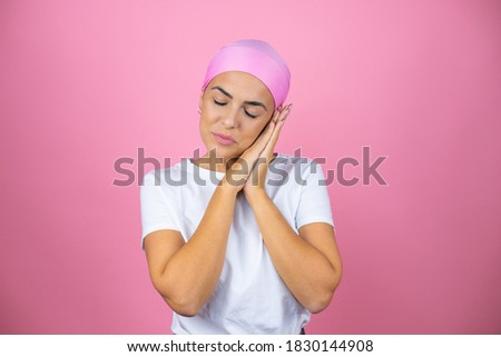 Young beautiful woman wearing pink headscarf over isolated pink background sleeping tired dreaming and posing with hands together while smiling with closed eyes.
