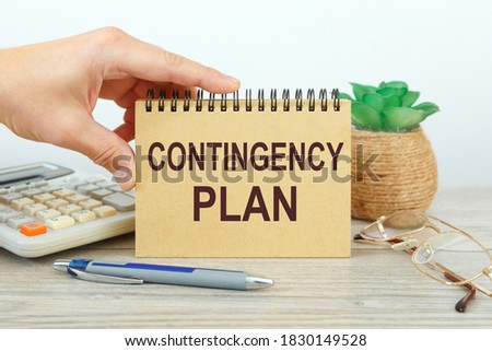 Notepad with text Contingency Plan on a white background, near calculator and office supplies. Business concept. Royalty-Free Stock Photo #1830149528