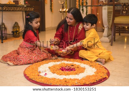 Mother making rangoli with kids on festival day Royalty-Free Stock Photo #1830153251
