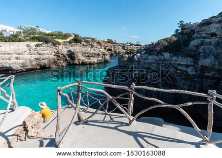 Turquoise waters of Cala en Brut, beach of Minorca, with a man with hat contemplating the view, Balearic Islands in Spain Royalty-Free Stock Photo #1830163088