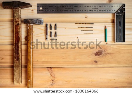 carpentry work. light wood background. wood texture. two hammers, a set of drills, a pencil and an iron corner lie on a wooden background. advertising poster. photo for blog. place for text.
