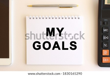 Notepad with text MY GOALS on a white background, near calculator, tablet and pen. Business concept.