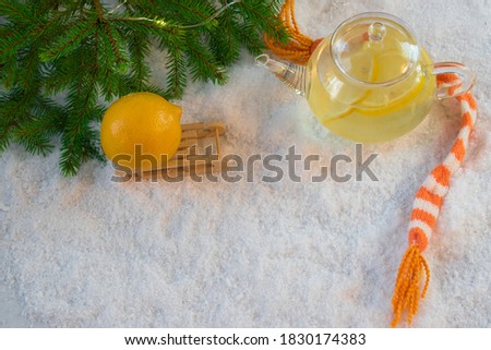 A pot of hot tea with lemon and a scarf in the snow. Banner. Space for text