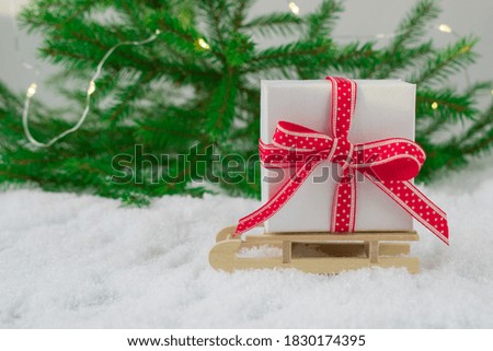 New year's frame. Christmas card. Banner. Gift box on a wooden sled on the snow on the background of green branches.