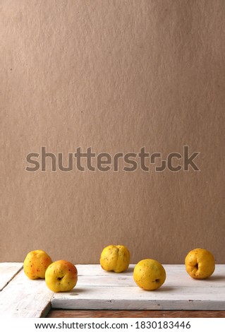 Composition of chaenomeles fruits  with copy space. Still life of Maules quince ripe fruits on white wooden table with empty wall.  Edible citrus fruits.