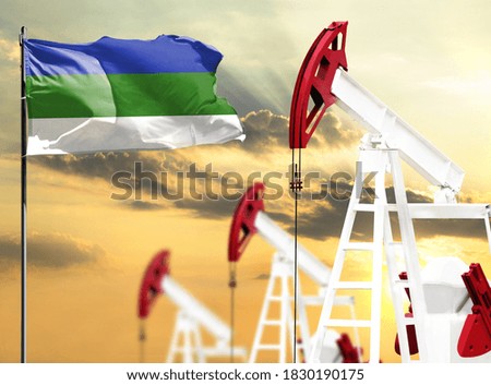 Oil rigs against the backdrop of the colorful sky and a flagpole with the flag of Komi. The concept of oil production, minerals, development of new deposits.