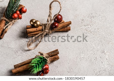Cinnamon sticks with red beads on textured and grey background